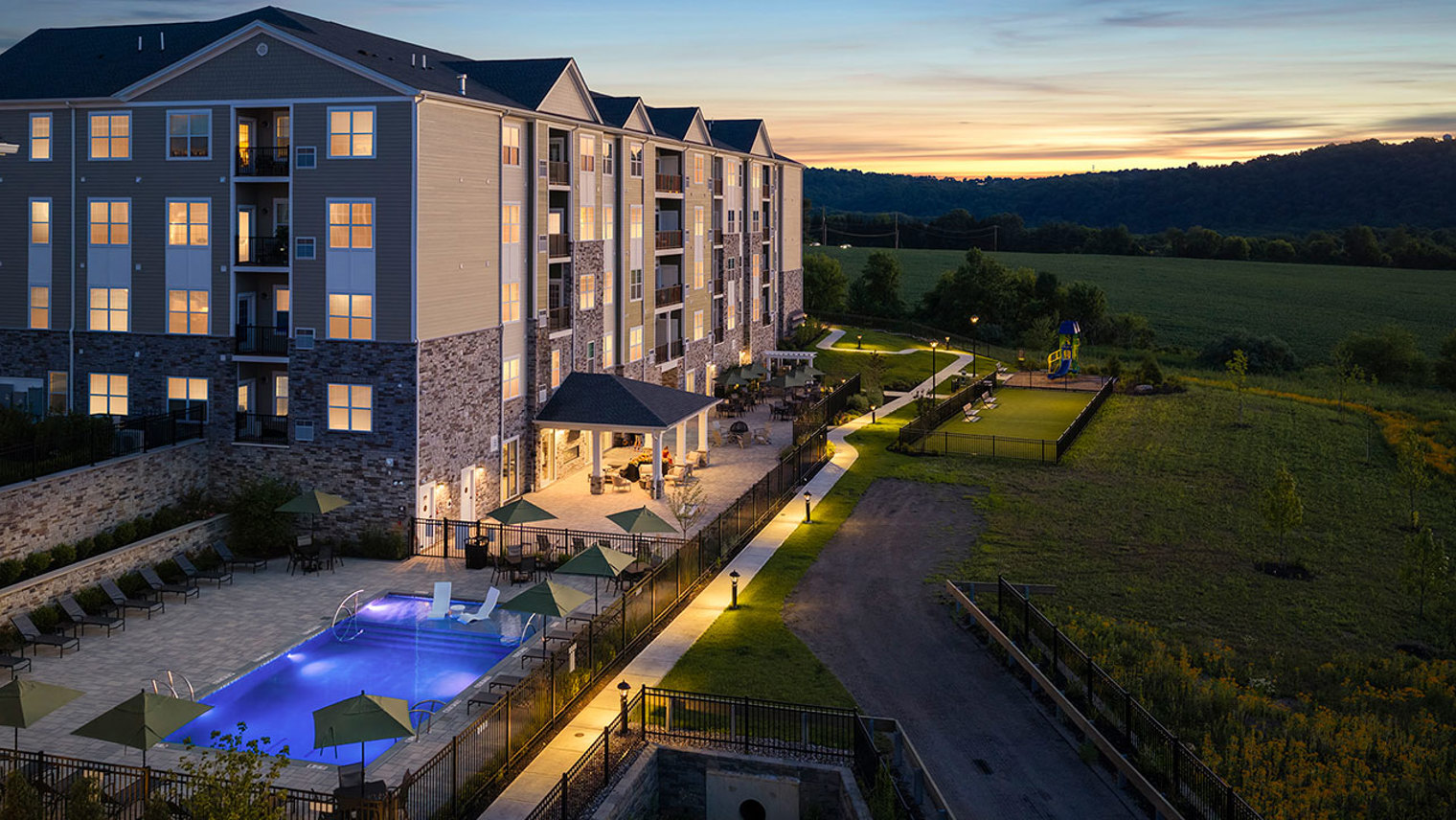 Monte View at Pohatcong Twilight view of pool, pavilion, tot lot, and bark park at luxury apartment community in Pohatcong, NJ – Monte View at Pohatcong